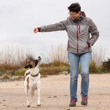 Eine junge Frau geht mit ihrem Hund am Strand spazieren.