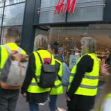 Mehrere Menschen in gelben Westen vor einer H&M-Filiale