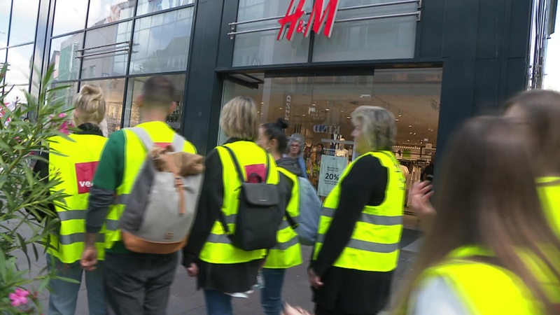 Mehrere Menschen in gelben Westen vor einer H&M-Filiale