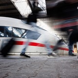 Reisende gehen an einem Bahnsteig an einem ICE der Deutschen Bahn vorbei
