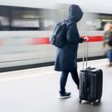 Eine Frau steht mit einem Koffer auf dem Bahnsteig im Hauptbahnhof Hannover, während ein ICE einfährt