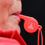 Das Logo der IG Metall ist bei einer Demonstration auf einer in einem Mund steckenden Trillerpfeife zu sehen.