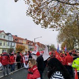 Eine Menschenmenge in größtenteils roten Jacken demonstriert auf einer Straße.