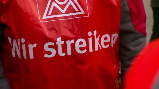 Die rote Jacke eines IG Metall Mitarbeiters mit der Aufschrift: "Wir streiken"