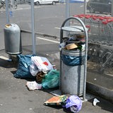 Abfall liegt neben Mülleimern auf einem Supermarktparkplatz.