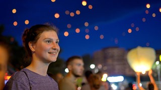 Junge Frau bei Veranstaltung, im Hintergrund Lichter