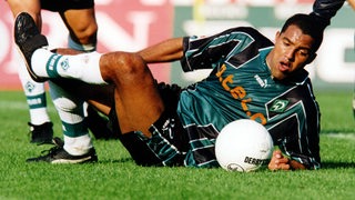 Werder-Spieler Ailton versucht auf dem Boden liegend den Ball zu spielen.
