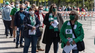 Werder-Fans warten in einer Schlange vor dem Weser-Stadion