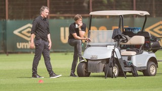 Frank Baumann und Clemens Fritz auf dem Bremer Trainingsplatz. Fritz stüztt seinen Fuß an Reifen eines Golf-Cart ab.