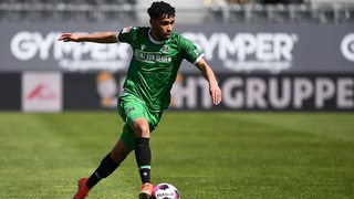 Offensivspieler Linton Maina für Hannover 96 im grünen Trikot am Ball.
