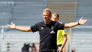 Werder-Trainer Markus Anfang steht fragend mit ausgebreiteten Armen an der Seitenlinie.