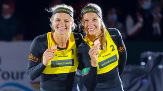 Beachvolleyballerin Kim Behrens und ihre Doppelpartnerin Sandra Ittlinger präsentieren ihre Bronzemedaillen.