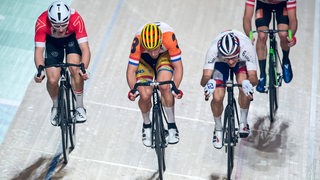 Radsportler fahren beim Sechs-Tage-Rennen über die Ziellinie.