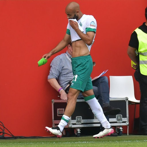 Werder-Kapitän Ömer Toprak verlässt nach einer Verletzung an der linken Wade das Spielfeld und wischt sich mit seinem Trikot frustriert das Gesicht.