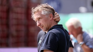 Werder-Sportchef Frank Baumann fasst sich vor dem Spiel in Karlsruhe nachdenklich an den Nacken.