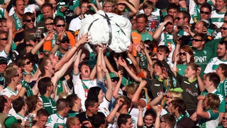 Werder-Fans in der Ostkurve halten eine große, weiße, selbstgebastelte Papierkugel hoch.