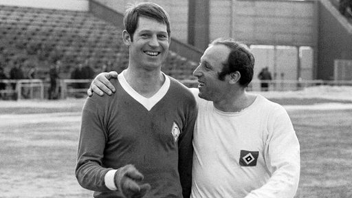 Werders Arnold "Pico" Schütz und HSV-Star Uwe Seeler legen 1971 lachend die Arme umeinander.