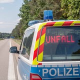 Ein Polizeiwagen steht auf einer leeren Autobahn. Im Rückfenster des Autos steht "Unfall".