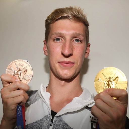 Schwimmstar Florian Wellbrock zeigt seine Medaillen.