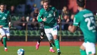 Werders U23-Kapitän Philipp Bargfrede steckt bei einem Pass in einer hektischen Spielphase konzentriert die Zunge zur Seite hinaus. 