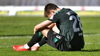 Werder-Spieler Ilia Gruev sitzt niedergeschlagen auf dem Rasen in Sandhausen.