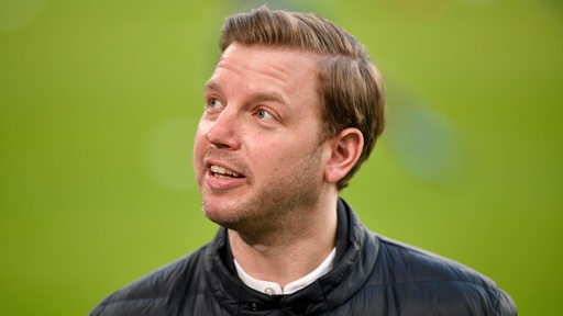 Ex-Werder-Trainer Florian Kohfeldt schaut lächelnd die Tribüne hoch.