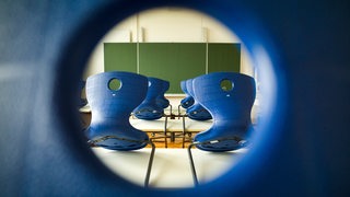 Blaue Stühle stehen auf den Tischen in einem Klassenzimmer