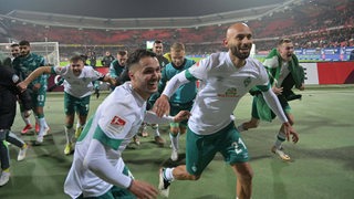 Die Werder-Spieler um Leonardo Bittencourt und Ömer Toprak stürmen nach dem Sieg in Nürnberg jubeln zu ihrer Fankurve.