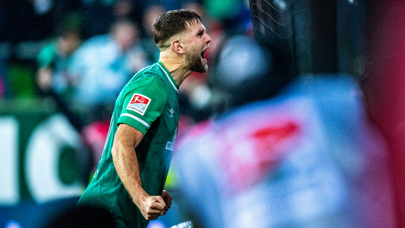 Werder-Stürmer Niclas Füllkrug feiert mit martialischer Geste seinen Treffer per Elfmeter vor der Fankurve.