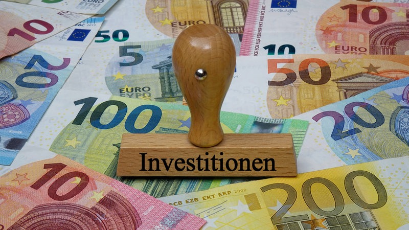 Ein Stempel mit dem Aufdruck "Investitionen" steht auf Geldscheinen