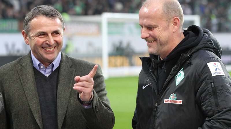 Wolfsburg-Manager Klaus Allofs lächelnd vor dem Spiel gegen Werder im Interview neben Trainer Thomas Schaaf.