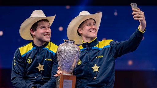 Die frischgebackenen Tischtennis-Weltmeister im Doppel Mattias Falck und Kristian Karlsson posieren mit Pokal, Medaillen und Cowboy-Hüten für ein Siegerselfie.