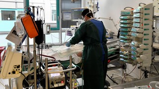 Ein Arzt kümmert sich um die Überwachung eines Patienten, der an eine Lungenersatzmaschine angeschlossen ist.