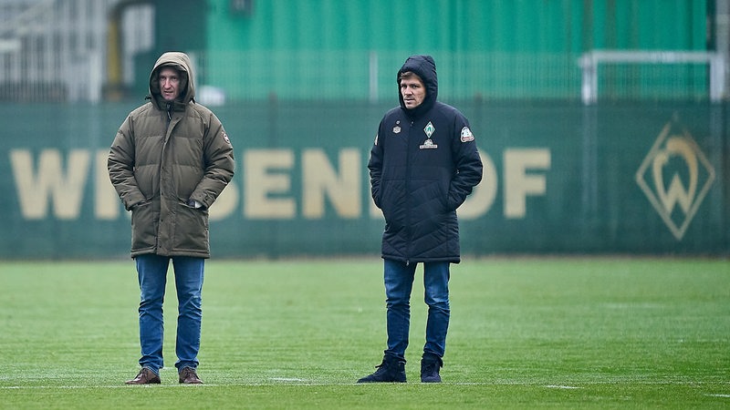 Frank Baumann und Clemens Fritz stehen in dicken Jacken auf dem Trainingsplatz nebeneinander.