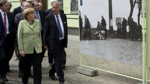 Bundeskanzlerin Angela Merkel und Kulturstaatsminister Bernd Neumann u.a. gehen an einem großen SW-Foto vorüber in der Stresemannstraße, Berlin