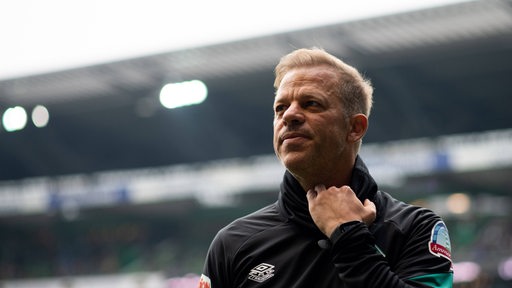 Ex-Werder-Trainer Markus Anfang zieht sich am T-Shirt.