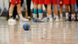 Ein Handball liegt in einer Turnhalle auf dem Boden.