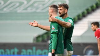 Werder-Stürmer Niclas Füllkrug legt seinen Arm um Sturmpartner Marvin Ducksch und erklärt ihm etwas.