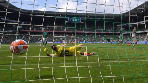 Felix Platte trifft zum 1:0 für Paderborn im Hinspiel gegen Werder. Das Tor ist aus der Hintertor-Perspektive zu sehen. Michael Zetterer liegt auf dem Boden und der Ball fliegt ins Netz.