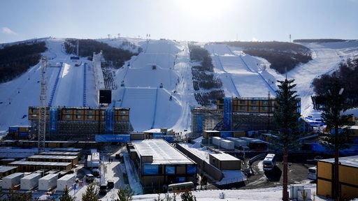 Blick von unten auf die Skiabfahrtspiste in Peking bei den Winterspielen mit Kunstschnee auf den Pisten.