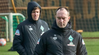 Ole Werner schaut fokussiert. Hinter ihm auf dem Trainingsplatz steht Clemens Fritz.