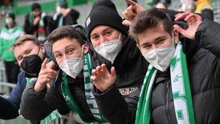 Junge Werder-Fans winken im Stadion in die Kamera.