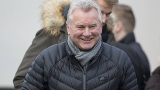 Ex-Werder-Profi Benno Möhlmann strahlt in schwarzer Winterjacke am Rande eines Spiels.