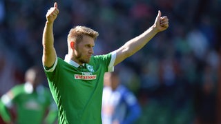 Werder-Profi Aaron Hunt reckt in Richtung der Fans beide Daumen in die Höhe.