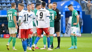 Schiedsrichter Daniel Siebert diskutiert nach einer strittigen Entscheidung mit Werder- und HSV-Spielern.