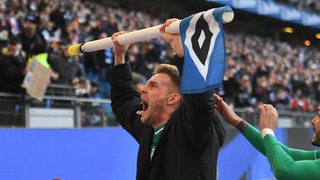 Werder-Torschütze Marvin Ducksch feiert mit hochgereckter HSV-Eckfahne mit lautem Gebrüll den Sieg.