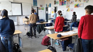 Schülerinnen und Schüler legen eine Schweigeminute ein.
