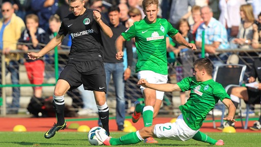 Marnon Busch grätscht im Spiel gegen den VfB Lübeck 2013. Niclas Füllkrug schaut zu.
