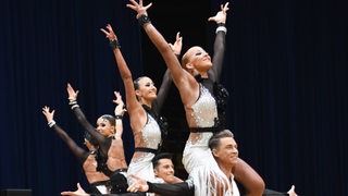 Die Lateinformation des Bremer Grün-Gold-Clubs in schwarz-weißen Kostümen bei einer Pose von "Emozioni", bei der die Tänzer ihrer Partnerinnen auf die Schultern gehoben haben.