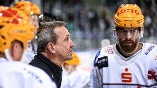 Pinguins-Coach Thomas Popiesch bei einer Besprechung mit seinen Spielern an der Bande.